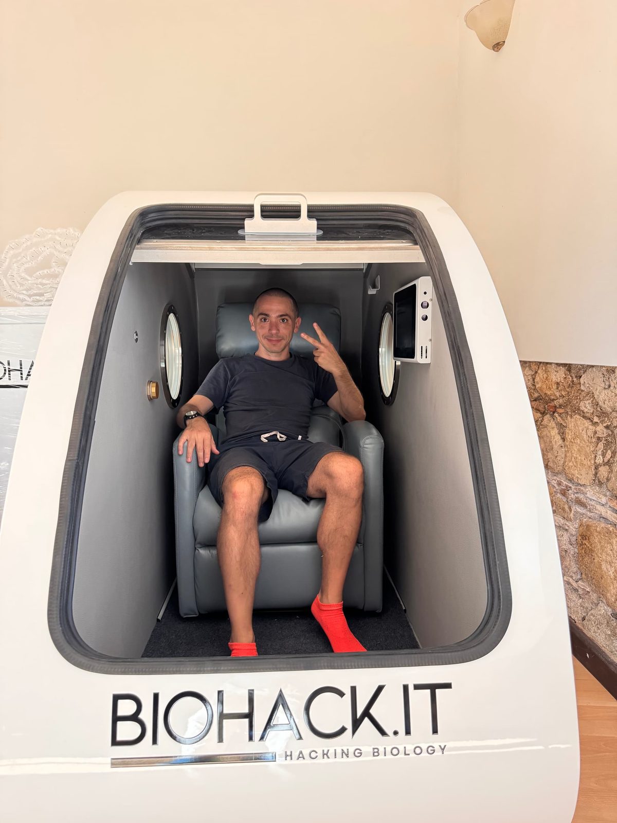 Fabio Pietrosanti sitting inside his hyperbaric chamber, which carries the BIOHACK.IT logo